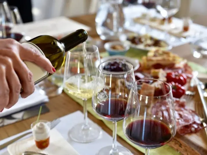 Pouring white and red wine in glasses at Chiappini Winery (Bio)